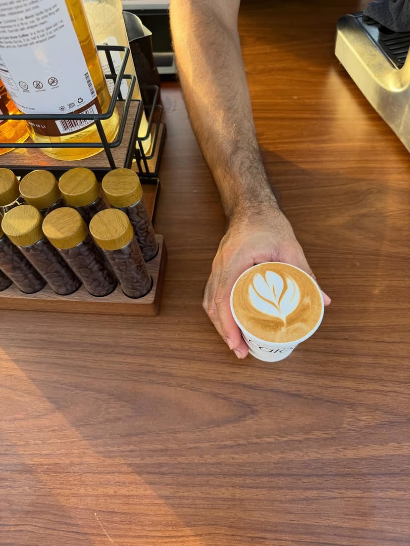 Barista entregando un latte en la barra de Caféalo